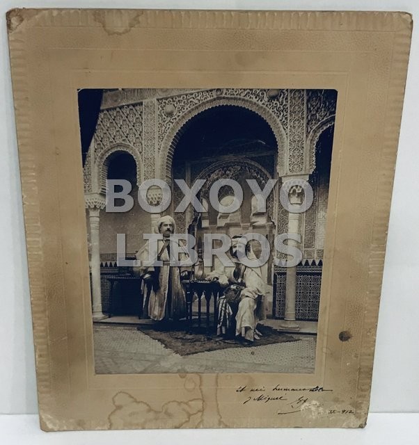 Fotografía de escena de maurofilia o 'a la morisca' de dos caballeros ataviados con decorado de la Alhambra con el Patio de los Leones de fondo en 1912